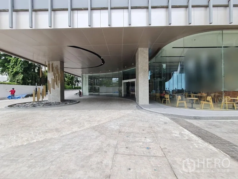 Retail Space for rent - Building entrance with wide canopy, cafe seating and driveway in front of the retail zone.