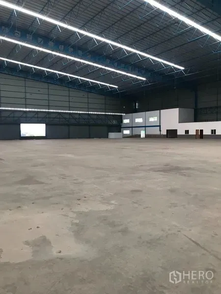 Warehouse for rent in Samut Prakan - Expansive warehouse interior with high-clearance steel truss roof, bright LED lighting, and polished concrete floor.