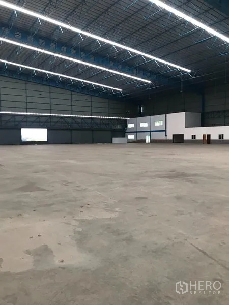 Warehouse for rent in Samut Prakan - Expansive warehouse interior with high-clearance steel truss roof, bright LED lighting, and polished concrete floor.