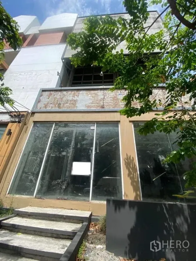 Shophouse for sale in Watthana, Bangkok - Street-facing multi-storey shophouse with wide floor-to-ceiling glass storefront and shaded entry in Ekkamai, Bangkok.