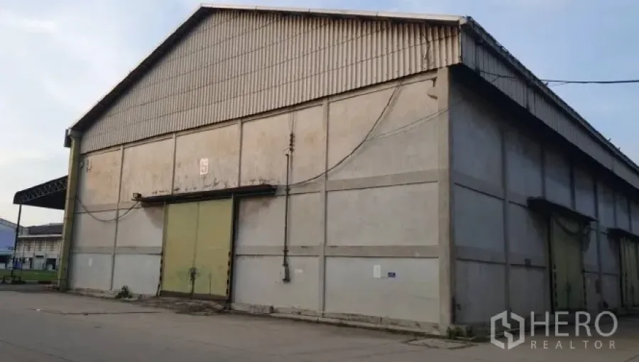 货栈 出租在Mueang Pathum Thani, Pathum Thani - 巴吞他尼府大型混凝土仓库外观，双坡屋顶与绿色推拉门。