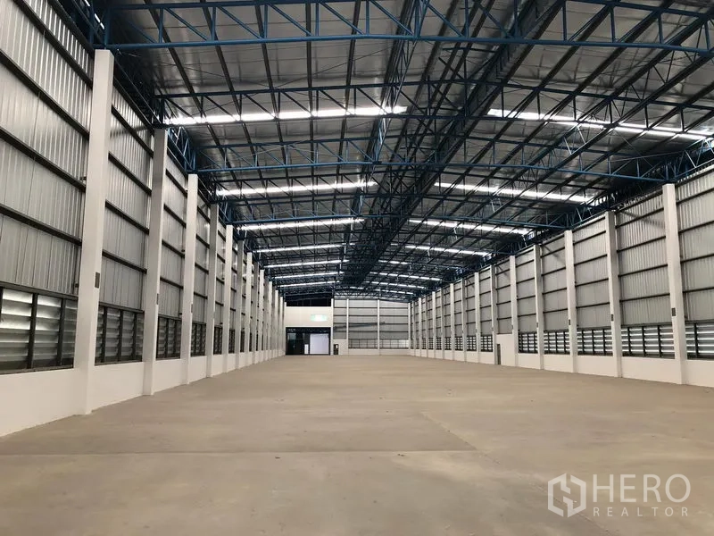 货栈 出租在Lat Krabang, Bangkok - 曼谷叻甲廊大型仓库内部，高钢桁架屋顶、天窗采光与开阔混凝土地面。