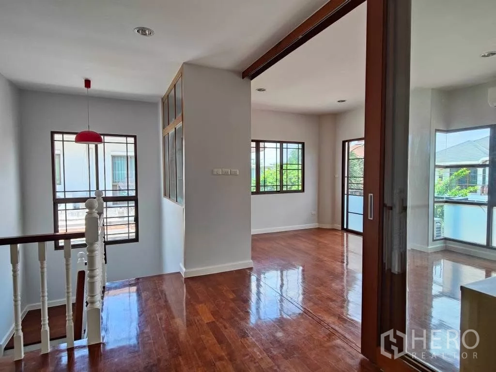 Detached House for rent or sale in Mueang Nonthaburi, Nonthaburi - Stair landing with red pendant light connecting to bright bedrooms.
