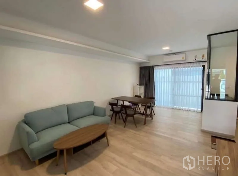 Townhouse for rent in Bang Phli, Samut Prakan - Open-plan living and dining room with sofa, dining table and sliding glass doors.
