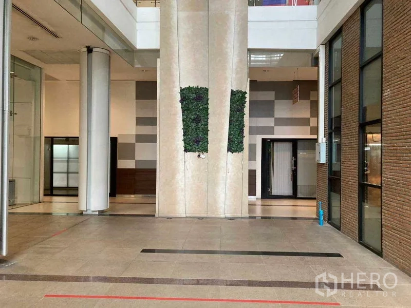 Retail Space for rent in Khlong Toei, Bangkok - Modern retail atrium with high ceiling, glass storefronts, brick accent wall, tiled floor, and vertical green wall feature.