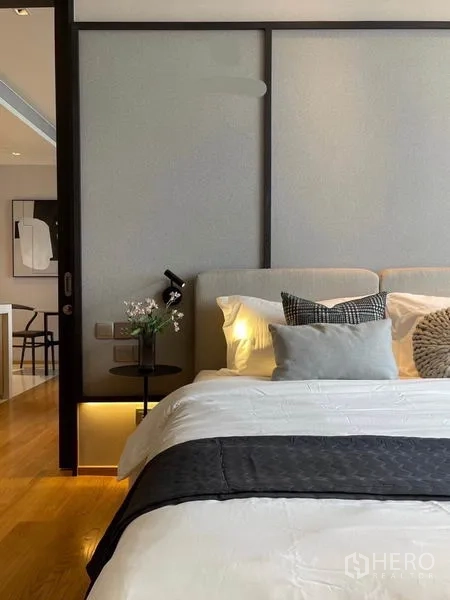 Condominium for rent in Khlong Toei, Bangkok - Cozy bedside view with upholstered headboard, soft lighting and decorative pillows.