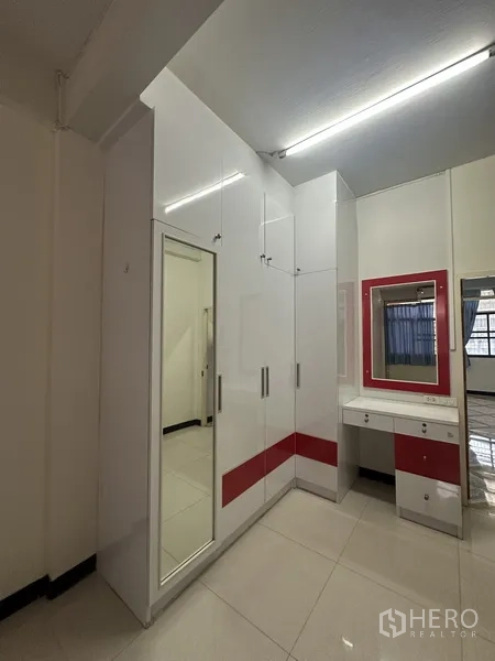Shophouse for rent or sale in Phra Khanong, Bangkok - Corner built-in closet with mirror and vanity inside a clean tiled bedroom.