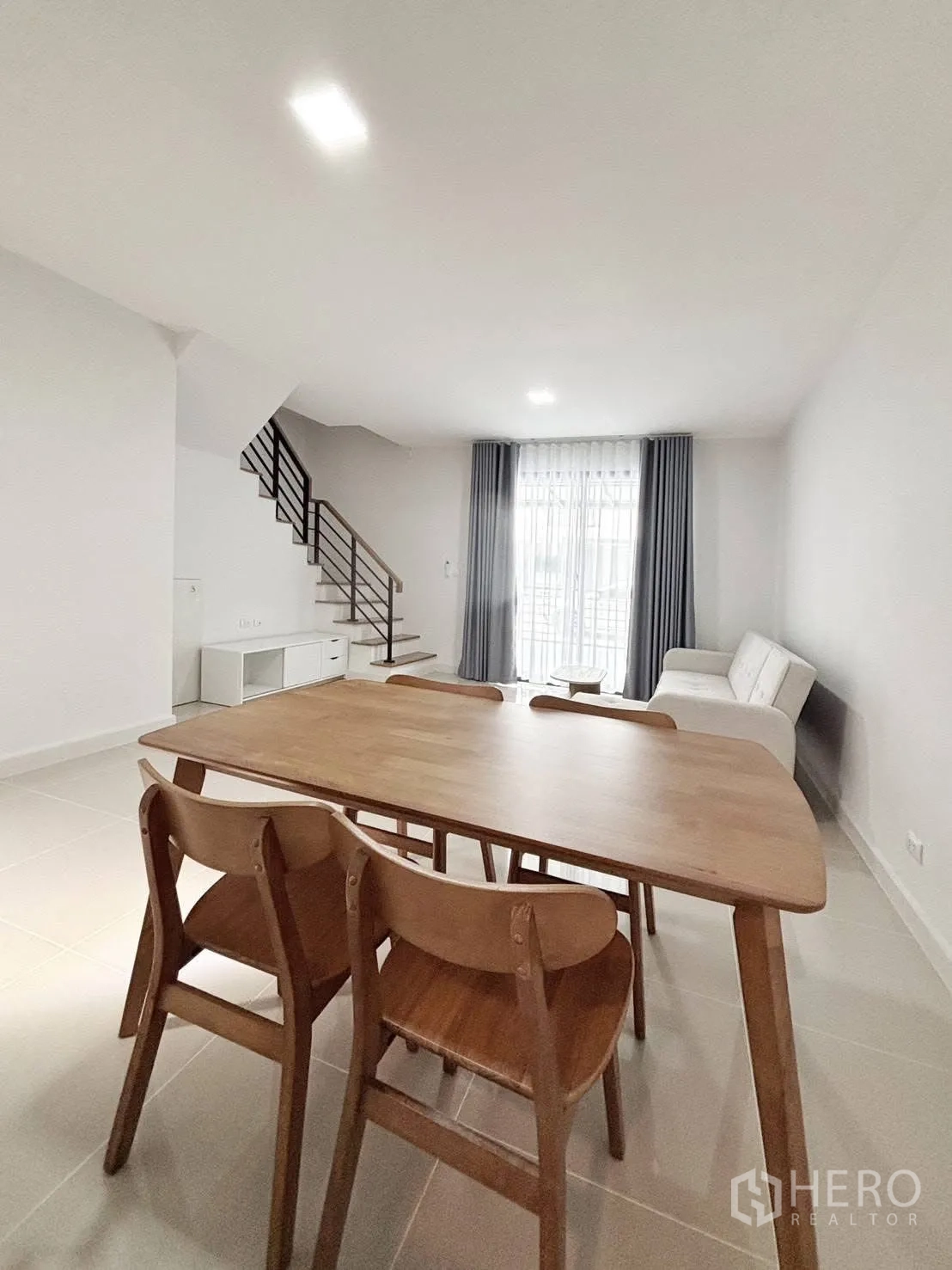 Townhouse for rent in Bang Phli, Samut Prakan - Dining table facing the living room and staircase in a bright open space.