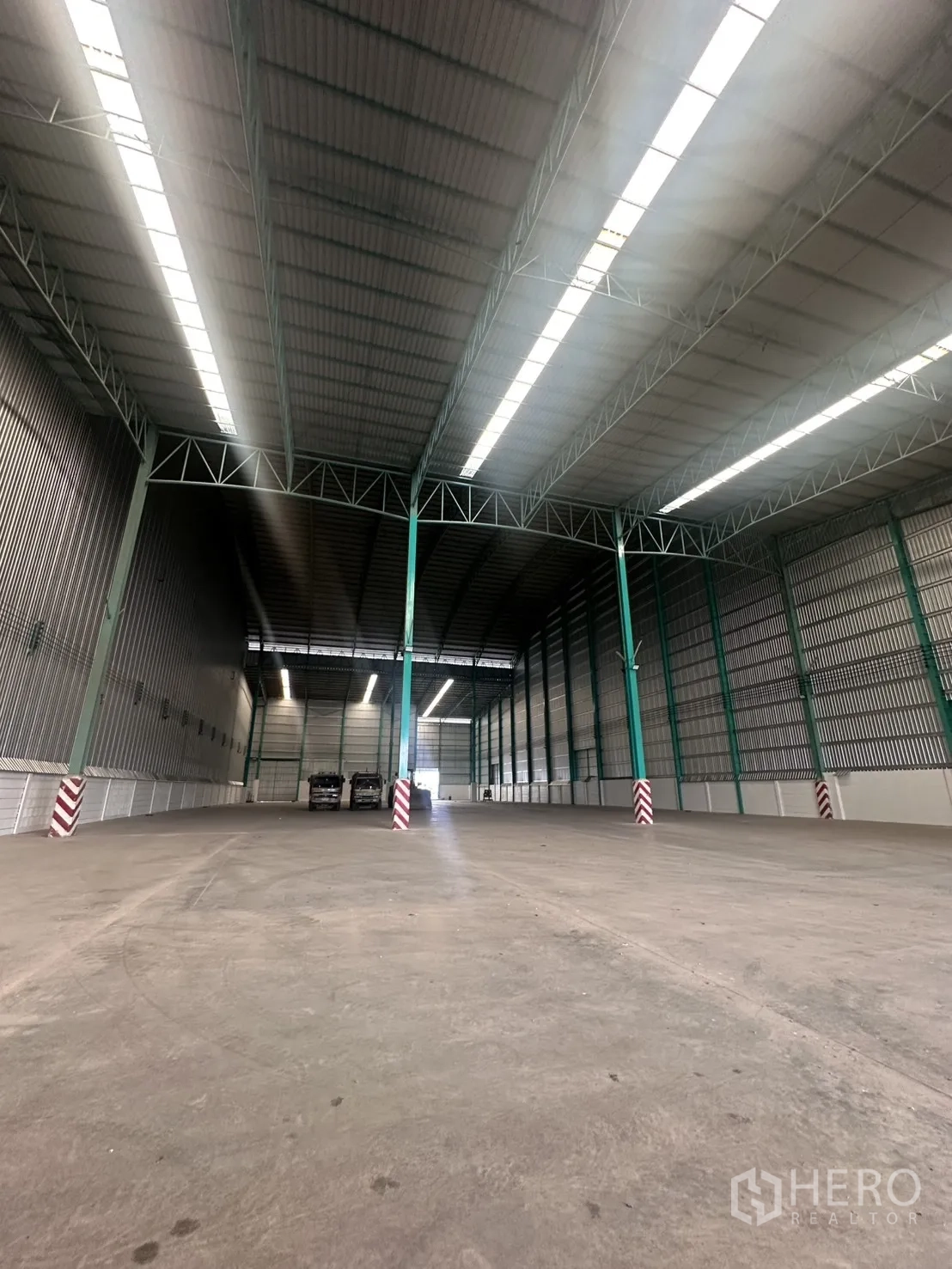 Warehouse for rent in Sai Noi, Nonthaburi - Open warehouse floor with high roof trusses, skylight panels, and durable concrete surface.