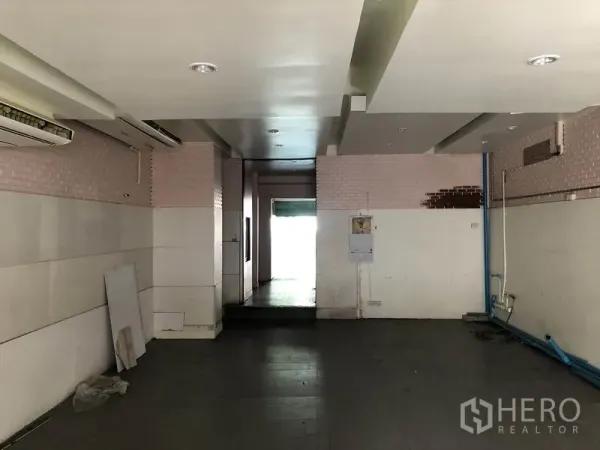 Home Office for rent or sale in Huai Khwang, Bangkok - Service area with low ceiling, wall panels and exposed blue plumbing leading to back entry.