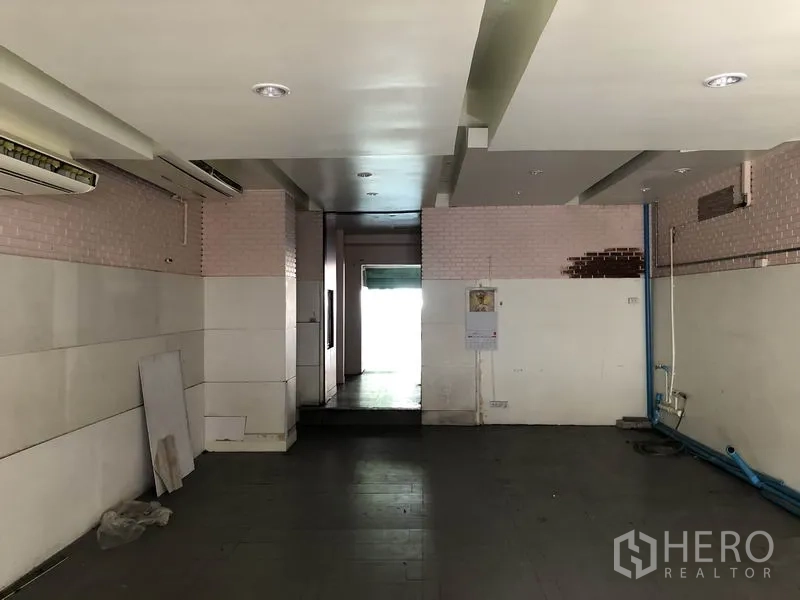 Home Office for rent or sale in Huai Khwang, Bangkok - Service area with low ceiling, wall panels and exposed blue plumbing leading to back entry.