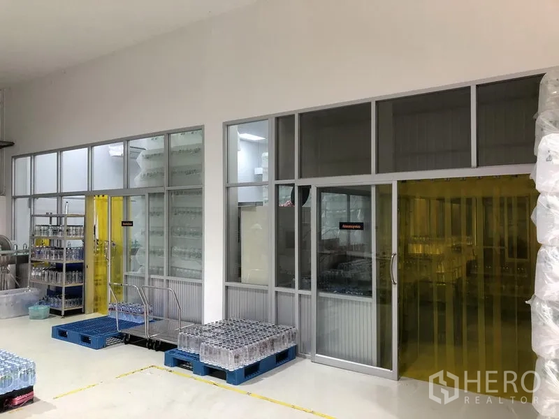 Factory for rent or sale in Wang Noi, Phra Nakhon Si Ayutthaya - Glass-partitioned processing rooms beside storage area with pallets and equipment.