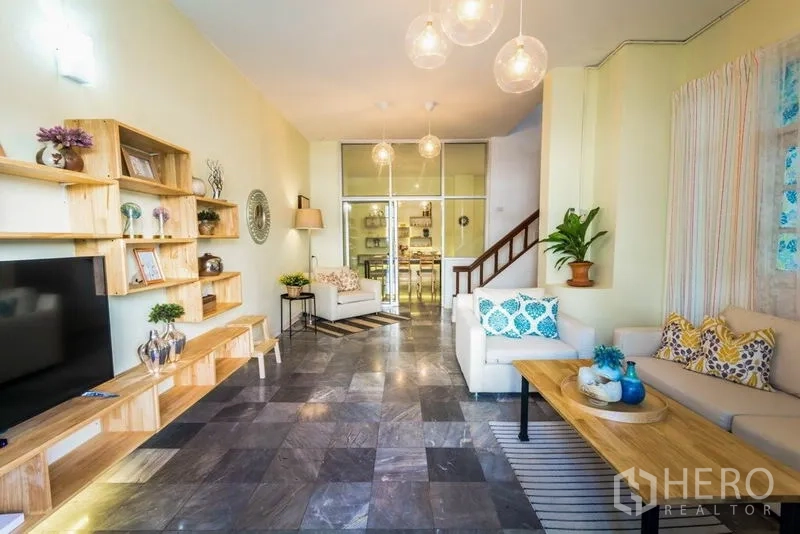 Home Office for rent in Suan Luang, Bangkok - Long living room with built-in wooden shelving, sofas and view to dining area.