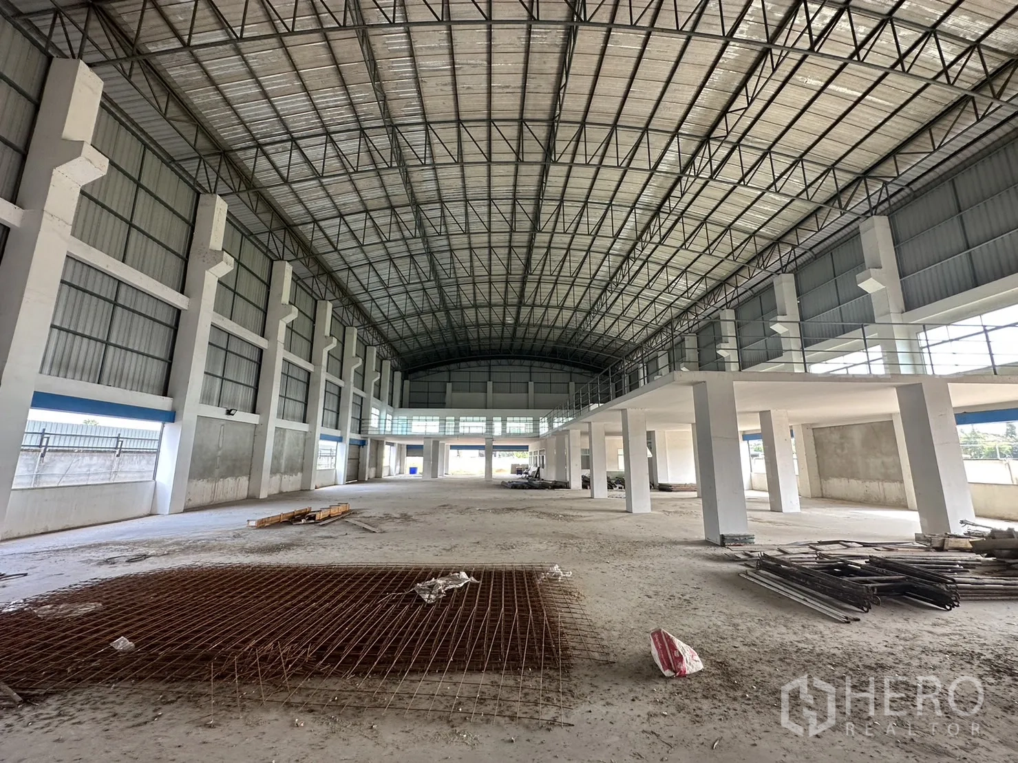 Factory for rent in Pak Kret, Nonthaburi - Interior aisle showing mezzanine railings, side roller doors and wide floor area.