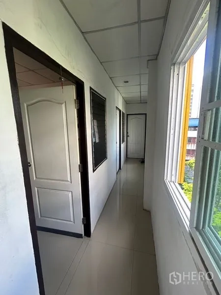 店屋 出租在Khlong Toei, Bangkok - 采光良好的走廊，推拉窗与多扇房门，可眺望社区。