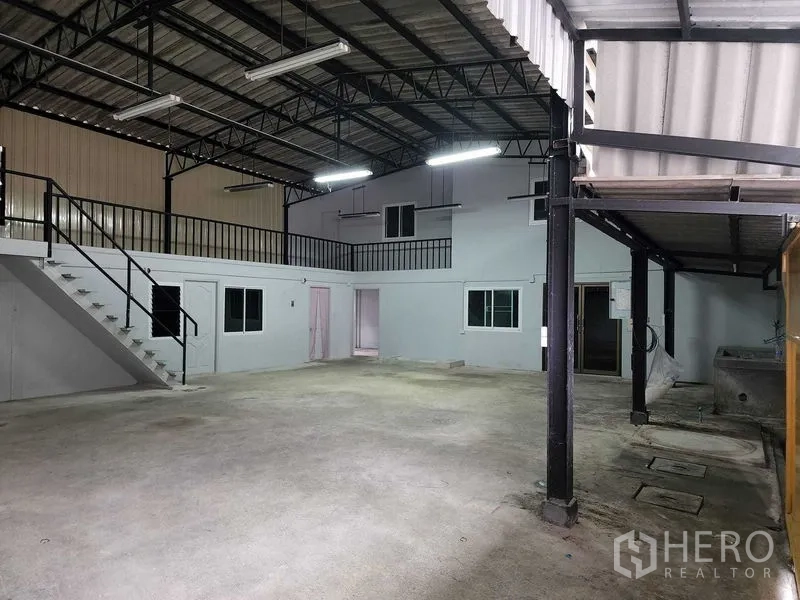 Warehouse for rent in Chatuchak, Bangkok - Full-span interior under steel roof trusses with bright lighting and side mezzanine.