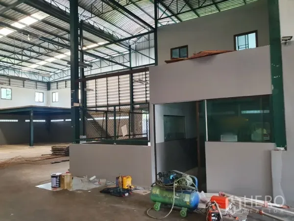 Factory for rent in Saphan Sung, Bangkok - Factory interior with steel frame, mezzanine office, glass windows and equipment on the floor.