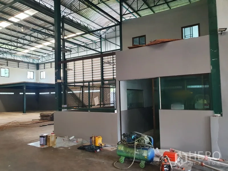 Factory for rent in Saphan Sung, Bangkok - Factory interior with steel frame, mezzanine office, glass windows and equipment on the floor.