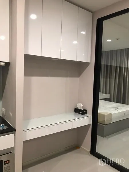 Condominium for rent in Pathum Wan, Bangkok - Wall-mounted storage and small work desk beside the bedroom entrance