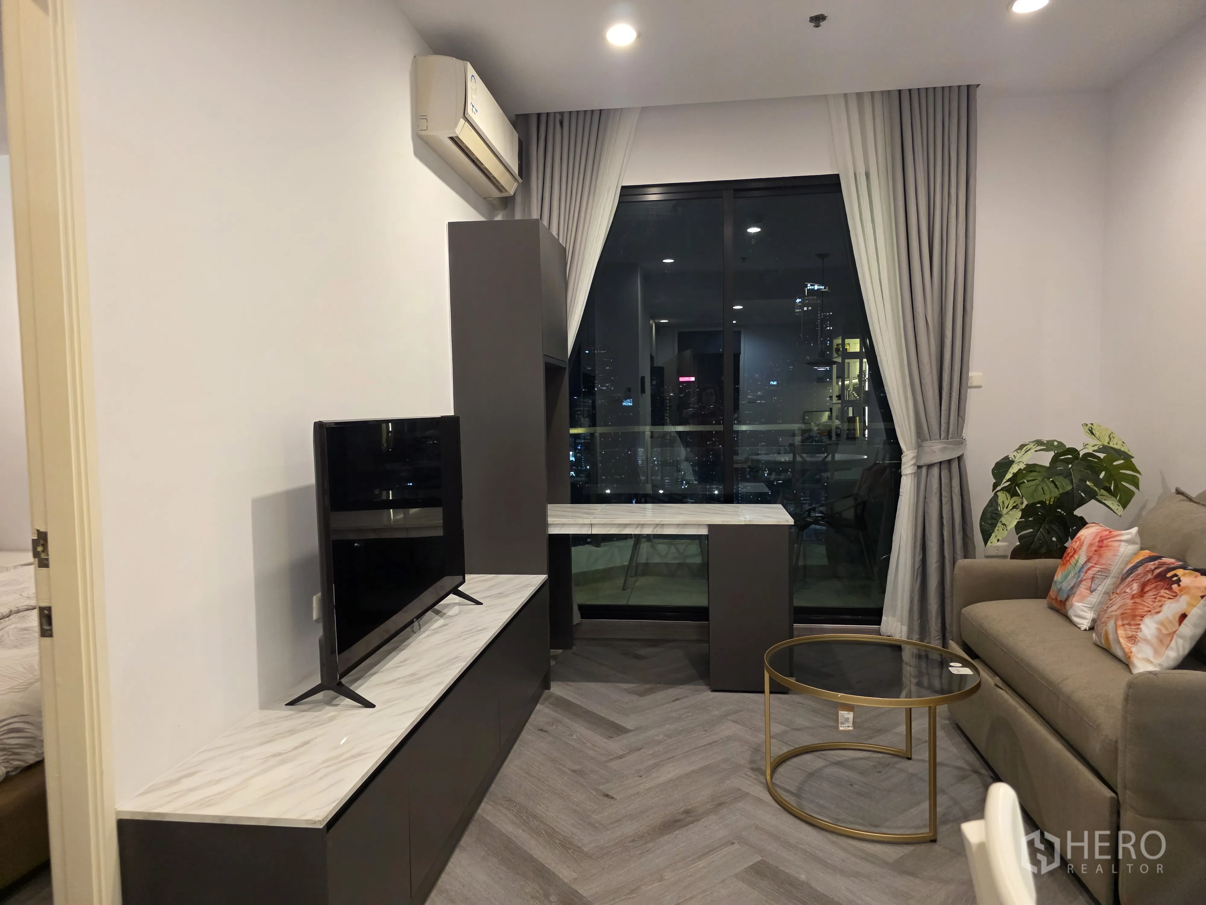 Condominium for rent in Bang Kapi, Bangkok - Living room featuring a sofa bed, TV unit, wall art, and large window.