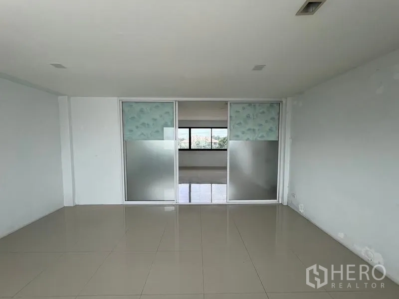 Warehouse for rent in Bang Phli, Samut Prakan - Empty office room with frosted glass sliding doors dividing spaces and shiny tiled floor.
