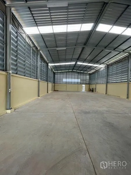 Warehouse for rent in Lam Luk Ka, Pathum Thani - Large open-plan warehouse interior with high ceiling, skylights and a concrete floor.