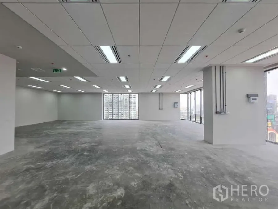 Office Space for rent in Chatuchak, Bangkok - Empty shell office with ceiling‑mounted lighting and tall windows framing city views.
