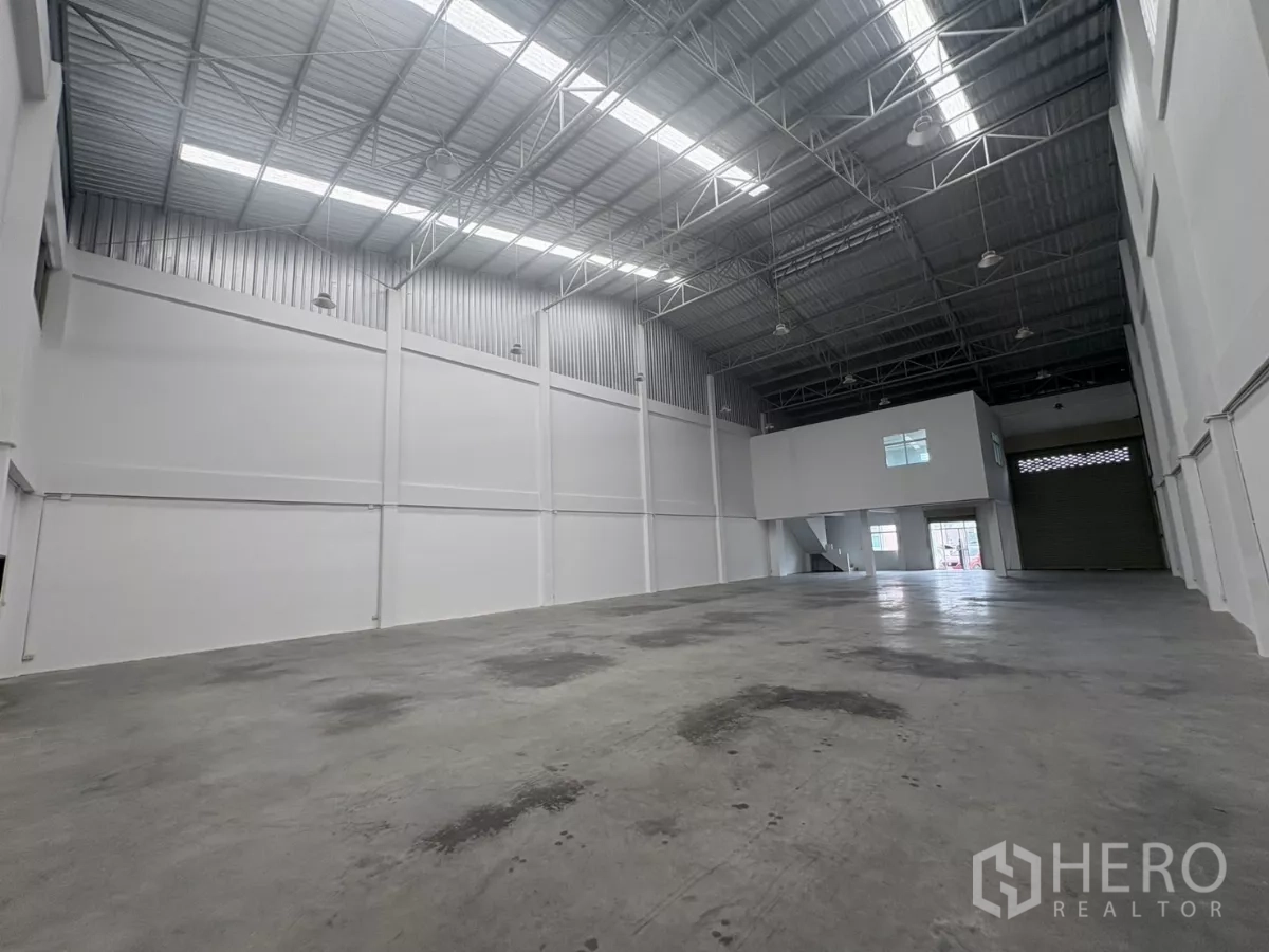 Factory for rent in Phra Samut Chedi, Samut Prakan - Wide warehouse view toward the mezzanine office and roller shutter loading bay.