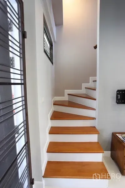 Townhouse for rent in Phra Khanong, Bangkok - Light-filled staircase with wooden steps and clean white walls.