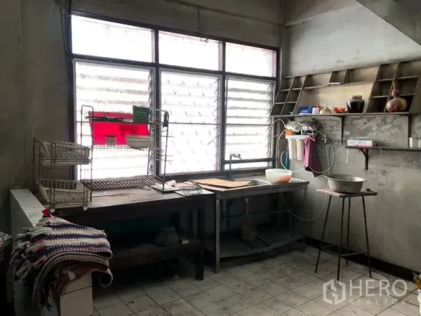 Shophouse for rent - Industrial-style kitchen with large louvered windows, metal counters, open shelving and tiled floor.