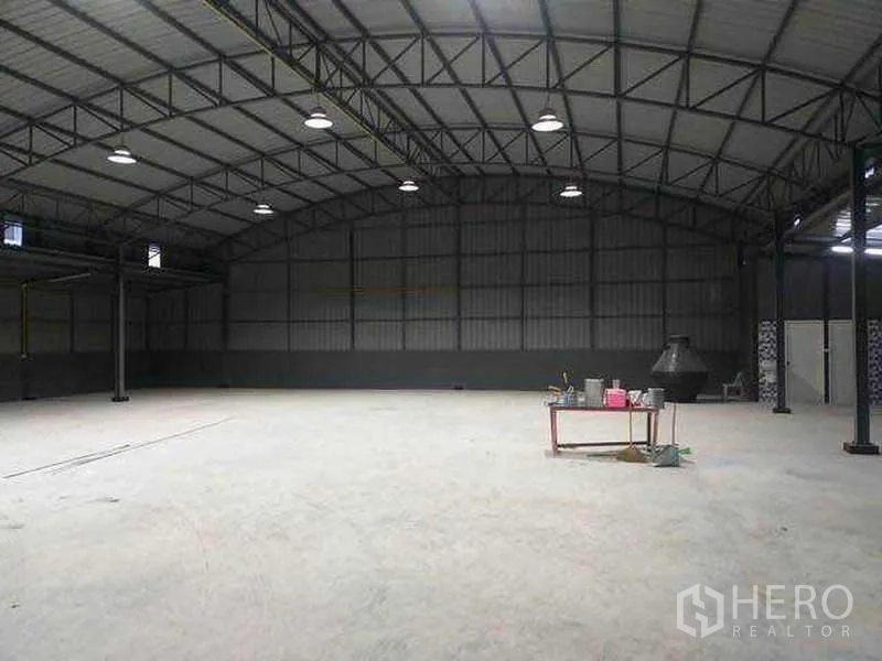 Warehouse for rent in Khlong Sam Wa, Bangkok - Wide concrete floor inside clear‑span warehouse with multiple ceiling lights and steel walls.