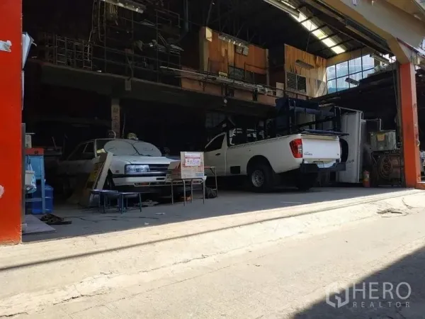 Warehouse for rent in Yan Nawa, Bangkok - Front bay of the warehouse with a white pickup, roll-up opening and covered workspace.
