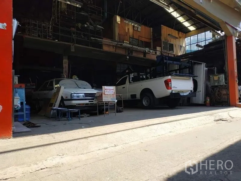 Warehouse for rent in Yan Nawa, Bangkok - Front bay of the warehouse with a white pickup, roll-up opening and covered workspace.