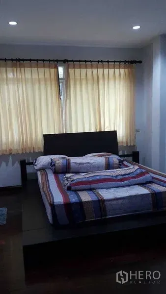 Detached House for sale in Bang Na, Bangkok - Cozy bedroom with platform bed, soft curtains and recessed lighting.