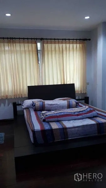 Detached House for sale in Bang Na, Bangkok - Cozy bedroom with platform bed, soft curtains and recessed lighting.