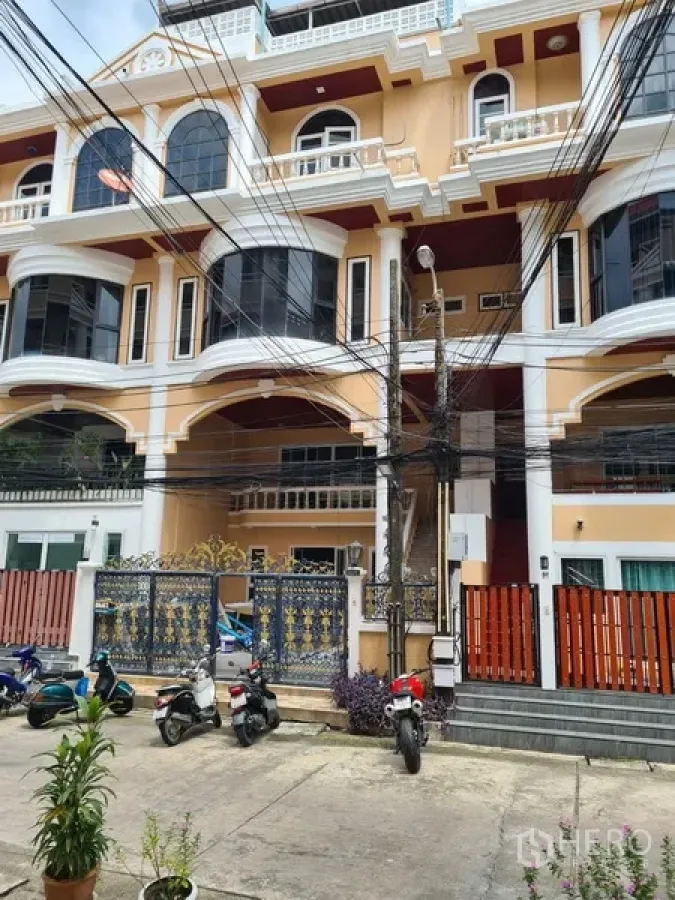 Townhouse for rent in Khlong Toei, Bangkok - Multi-storey townhouse exterior with cream facade, arched balconies and wrought-iron gate near BTS Thong Lo.