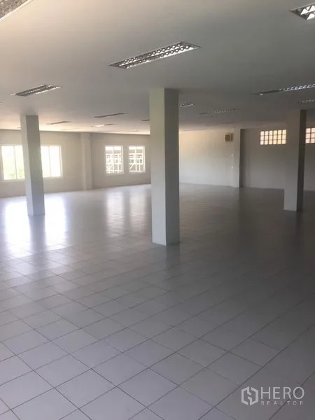 Factory for rent or sale in Samut Sakhon - Open-plan tiled office or multipurpose room with columns and windows providing natural light.