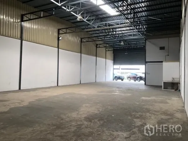 Warehouse for rent in Pak Kret, Nonthaburi - View toward the large roller shutter door with parking and loading area outside.