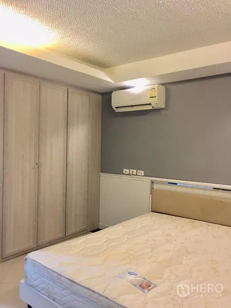Condominium for rent in Khlong Toei, Bangkok - Bedroom corner with built-in wardrobe and wall-mounted air conditioner.