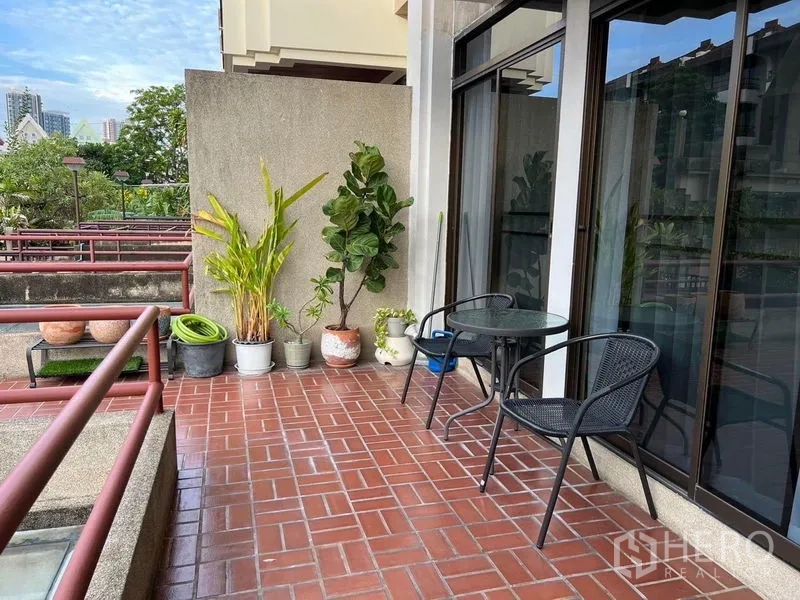 Townhouse for sale in Suan Luang, Bangkok - Private balcony with terracotta tiles, potted plants and glass doors, ideal for outdoor dining.
