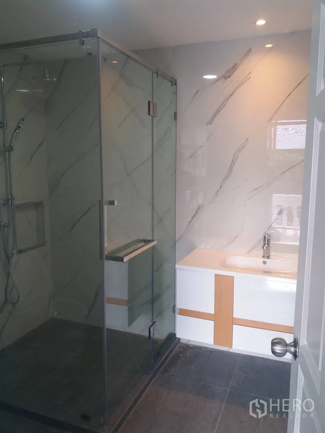 Townhouse for rent in Khlong Toei, Bangkok - Modern bathroom with glass shower enclosure, marble-look walls and a sleek vanity.