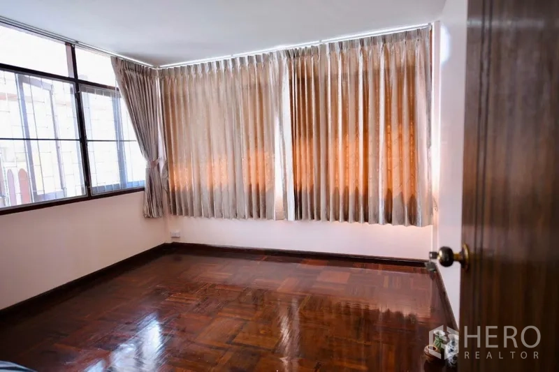 Detached House for rent in Bang Na, Bangkok - Bright bedroom with wide windows, full curtains and polished wooden flooring.