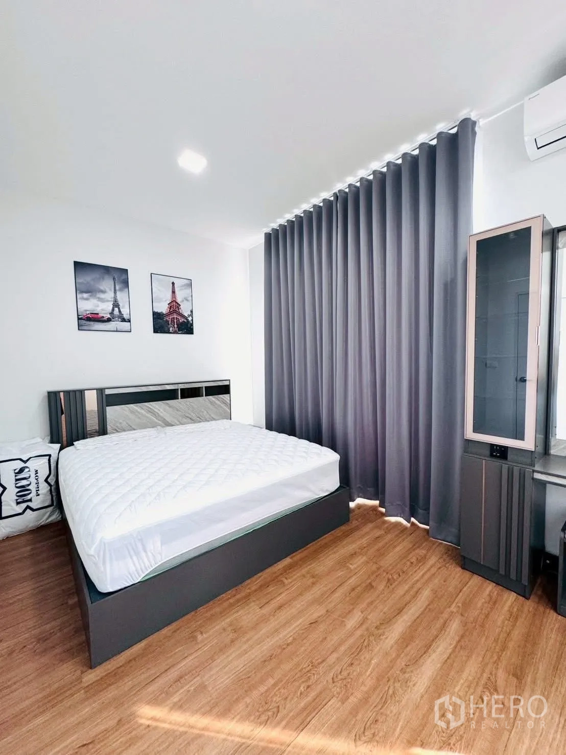 Townhouse for rent in Bang Phli, Samut Prakan - Sunlit bedroom with queen bed, corner windows, grey drapes and air conditioning.