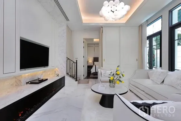 Detached House for rent or sale in Watthana, Bangkok - Bright living room with marble floors, built-in fireplace, TV wall and sofas.