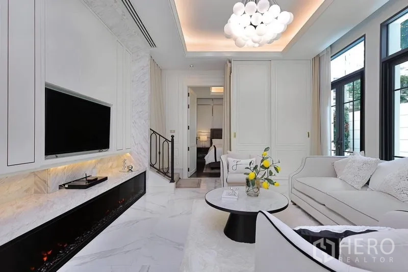 Detached House for rent or sale in Watthana, Bangkok - Bright living room with marble floors, built-in fireplace, TV wall and sofas.