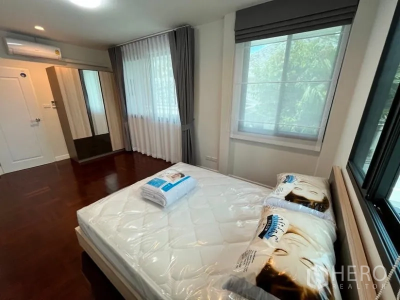 Detached House for rent in Phaya Thai, Bangkok - Cozy bedroom with windows on two sides, wardrobe and air-conditioning.