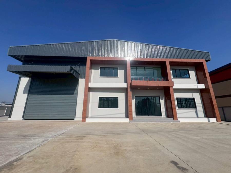 Factory for sale in Mueang Samut Sakhon, Samut Sakhon - Modern factory exterior with large roller shutter, two-storey office frontage and wide concrete yard under clear sky.
