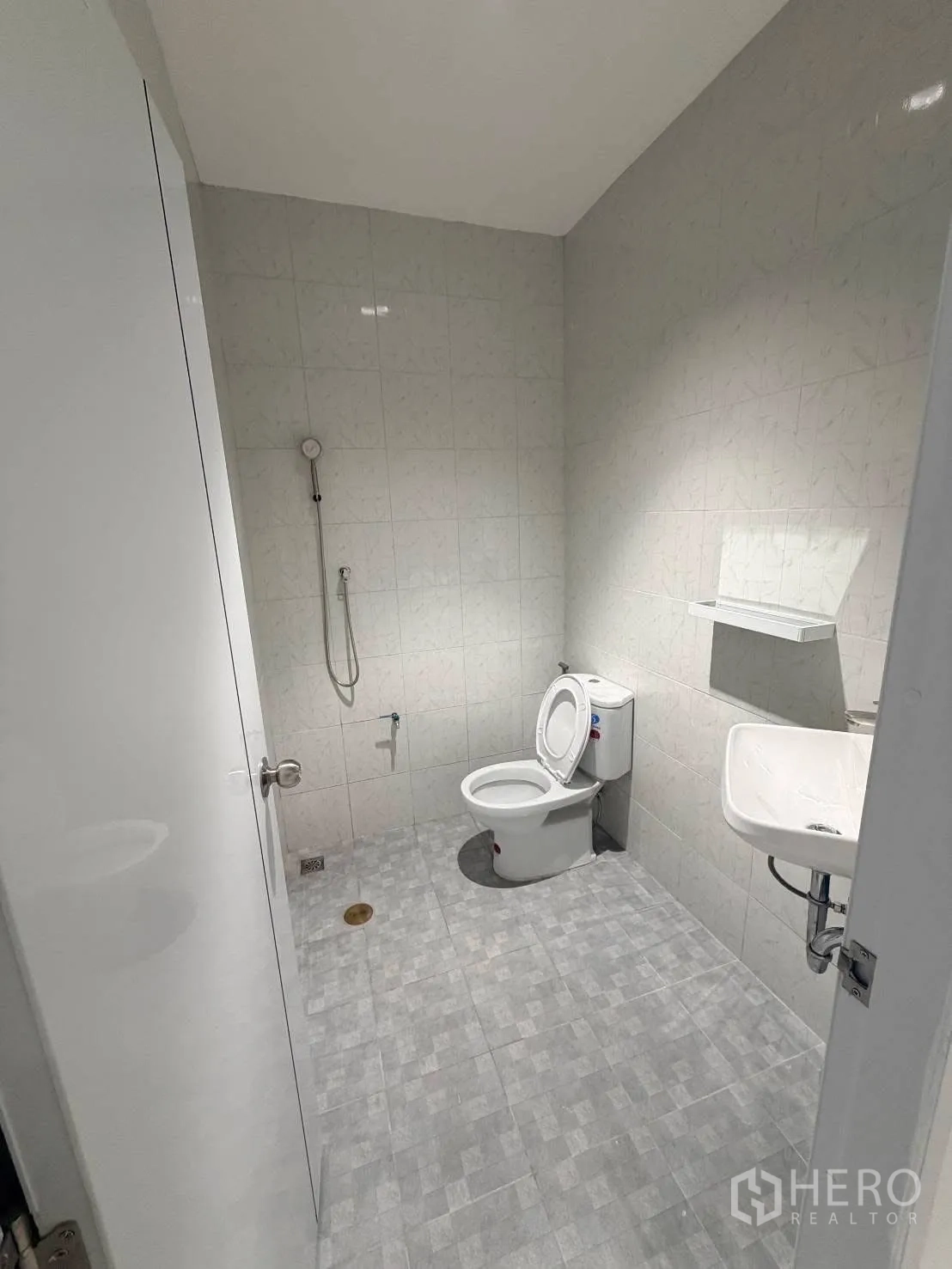 Townhouse for rent in Phra Khanong, Bangkok - Second tiled bathroom with toilet, sink, mirror and shower area.