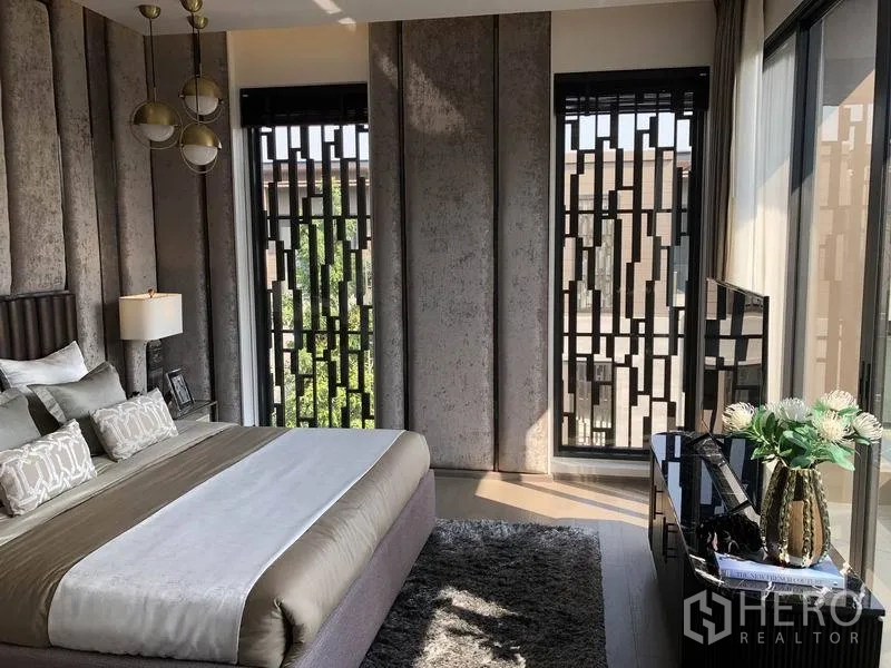 Detached House for sale in Bang Kapi, Bangkok - Secondary bedroom with textured wall panels, pendant lights, decorative window screens and area rug.