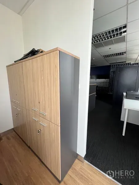 办公空间 出租在Huai Khwang, Bangkok - 现代办公室过道内的木纹与灰色储物柜。